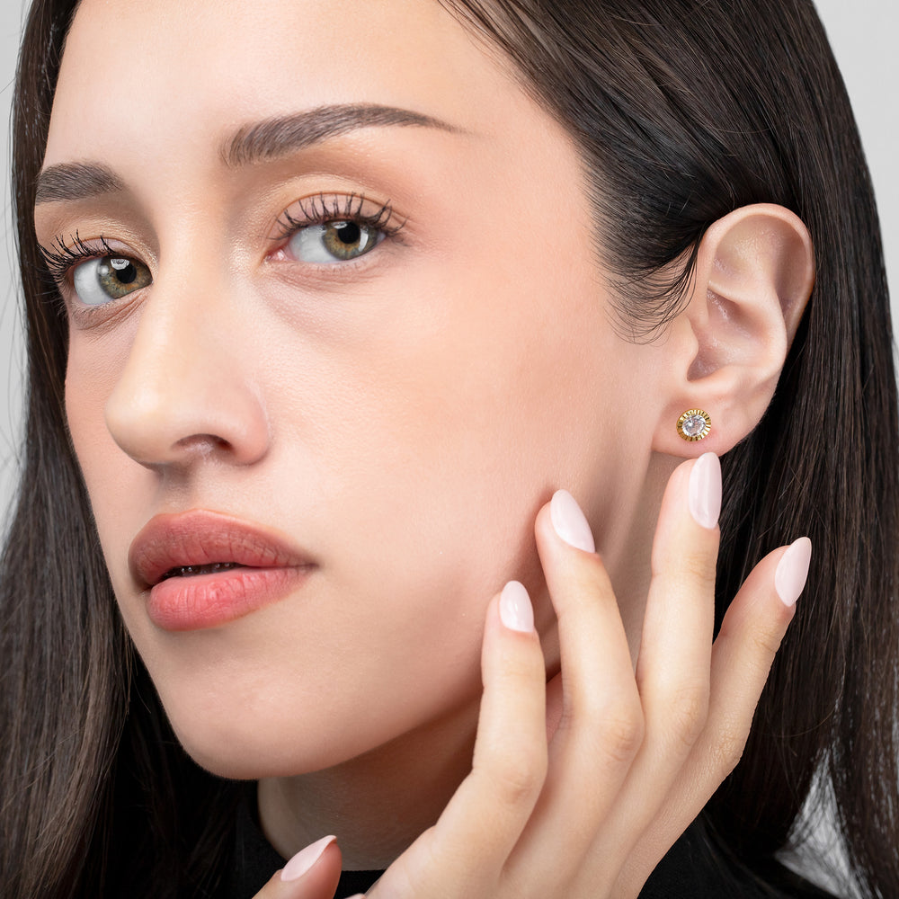 Close-up of a woman wearing a diamond earring with a neutral background