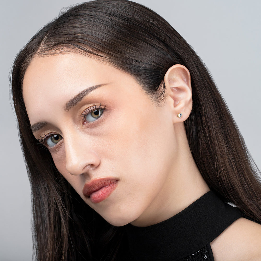 Close-up of a woman with long dark hair wearing a black top against a gray background