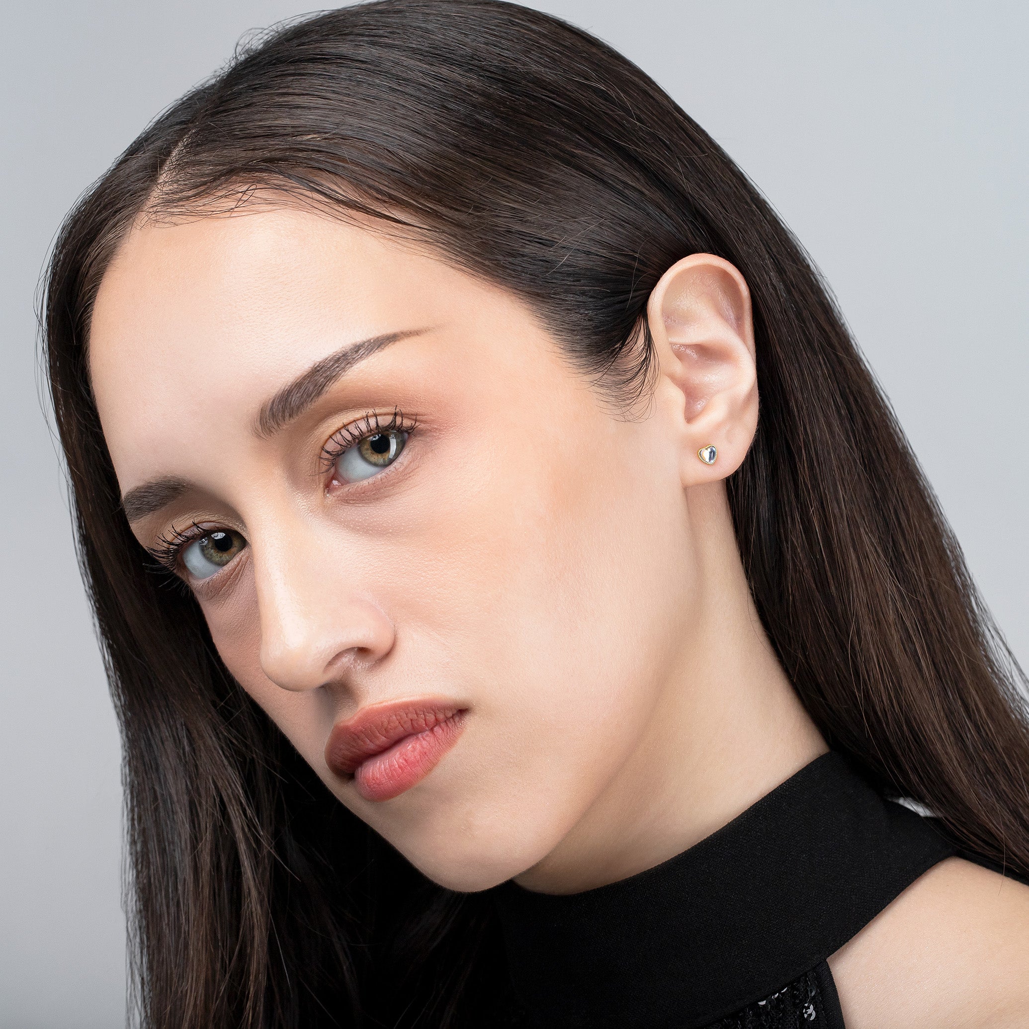 Close-up of a woman with long dark hair wearing a black top against a gray background