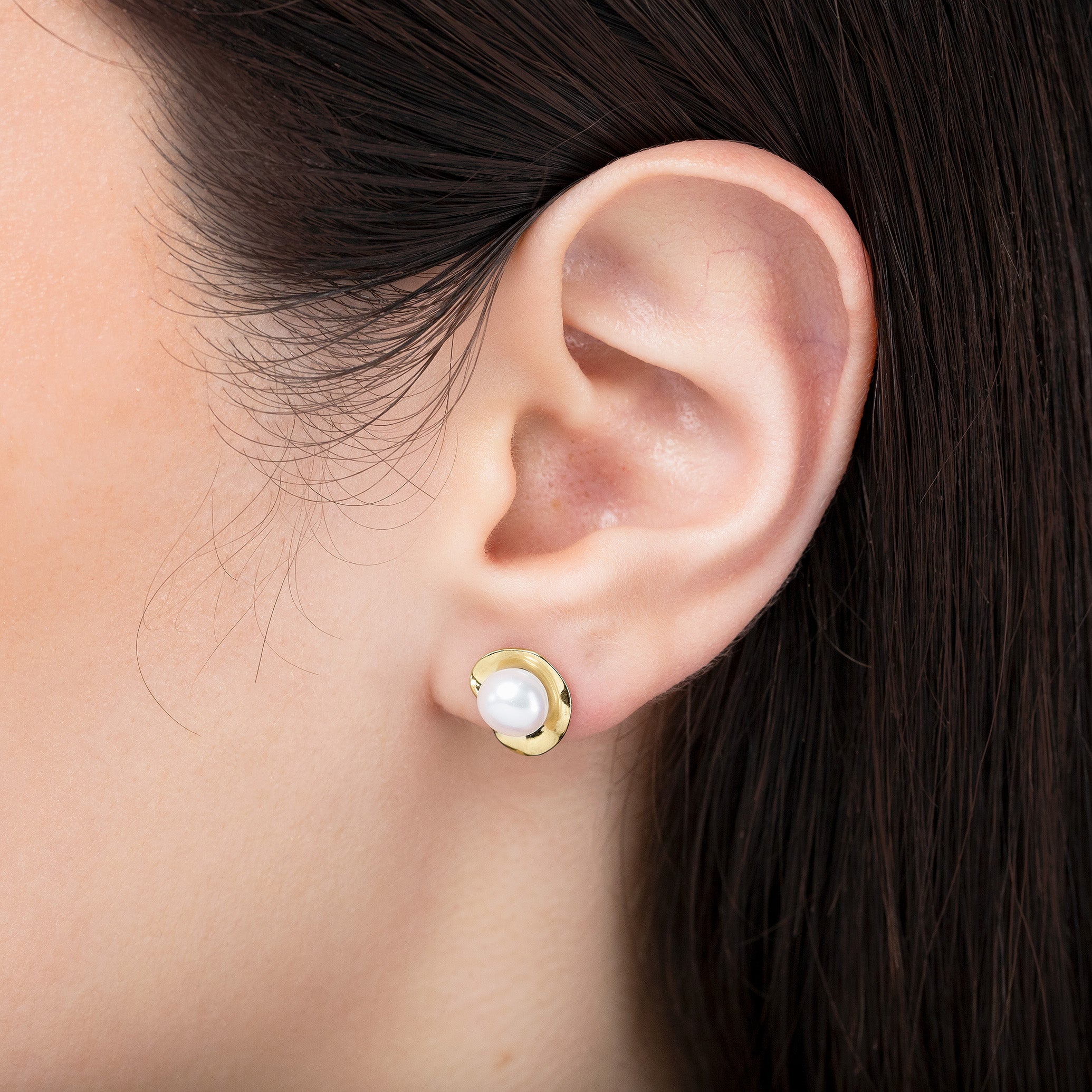 Gold earring with a pearl on an ear