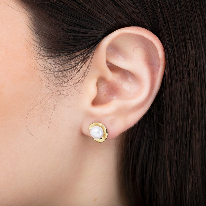 Gold earring with a pearl on an ear