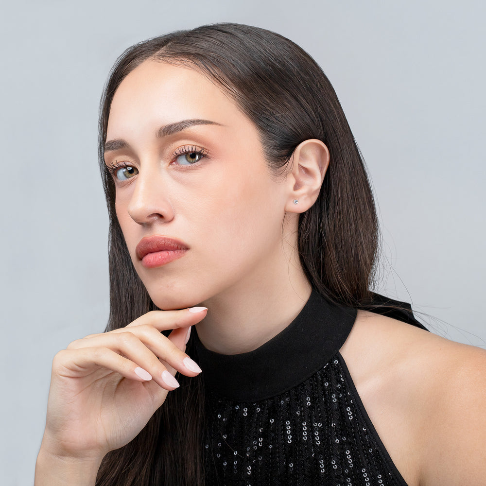 Woman with long dark hair wearing a black top against a light gray background