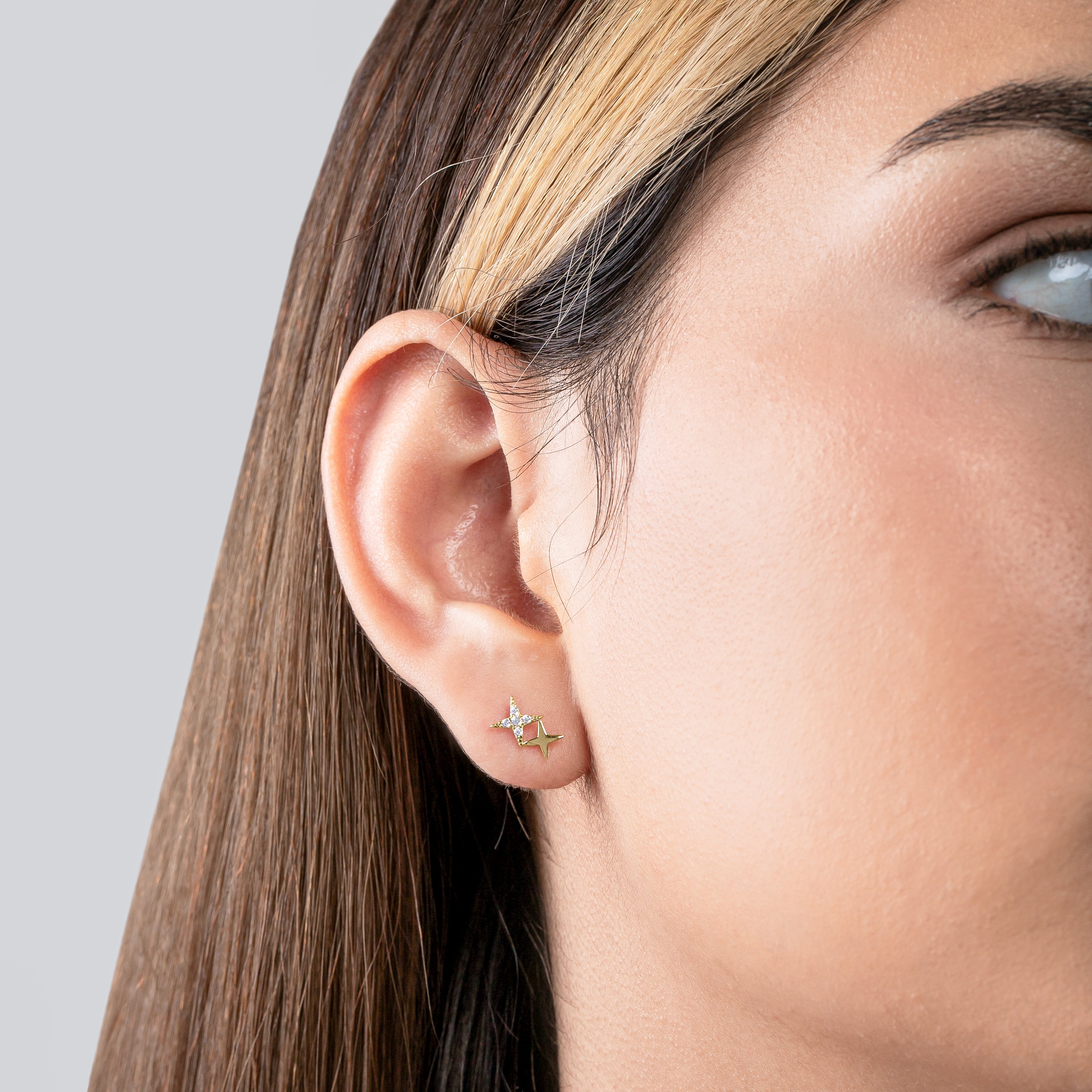 Close-up of a person wearing a star-shaped earring on a plain background