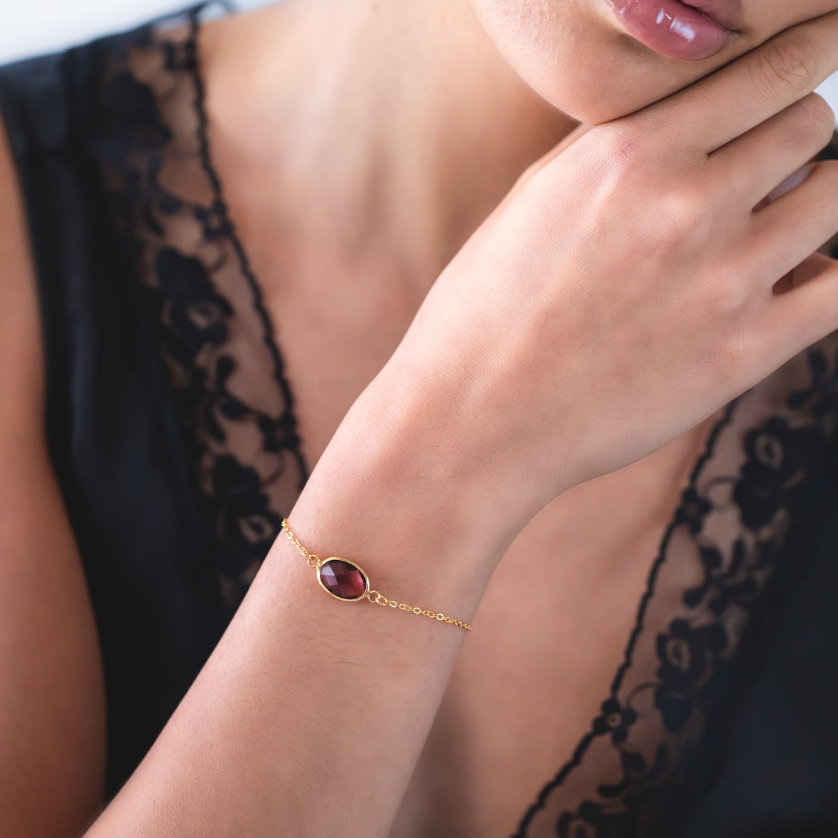 Gold-tone bracelet with dark pink faceted stone worn on a wrist
