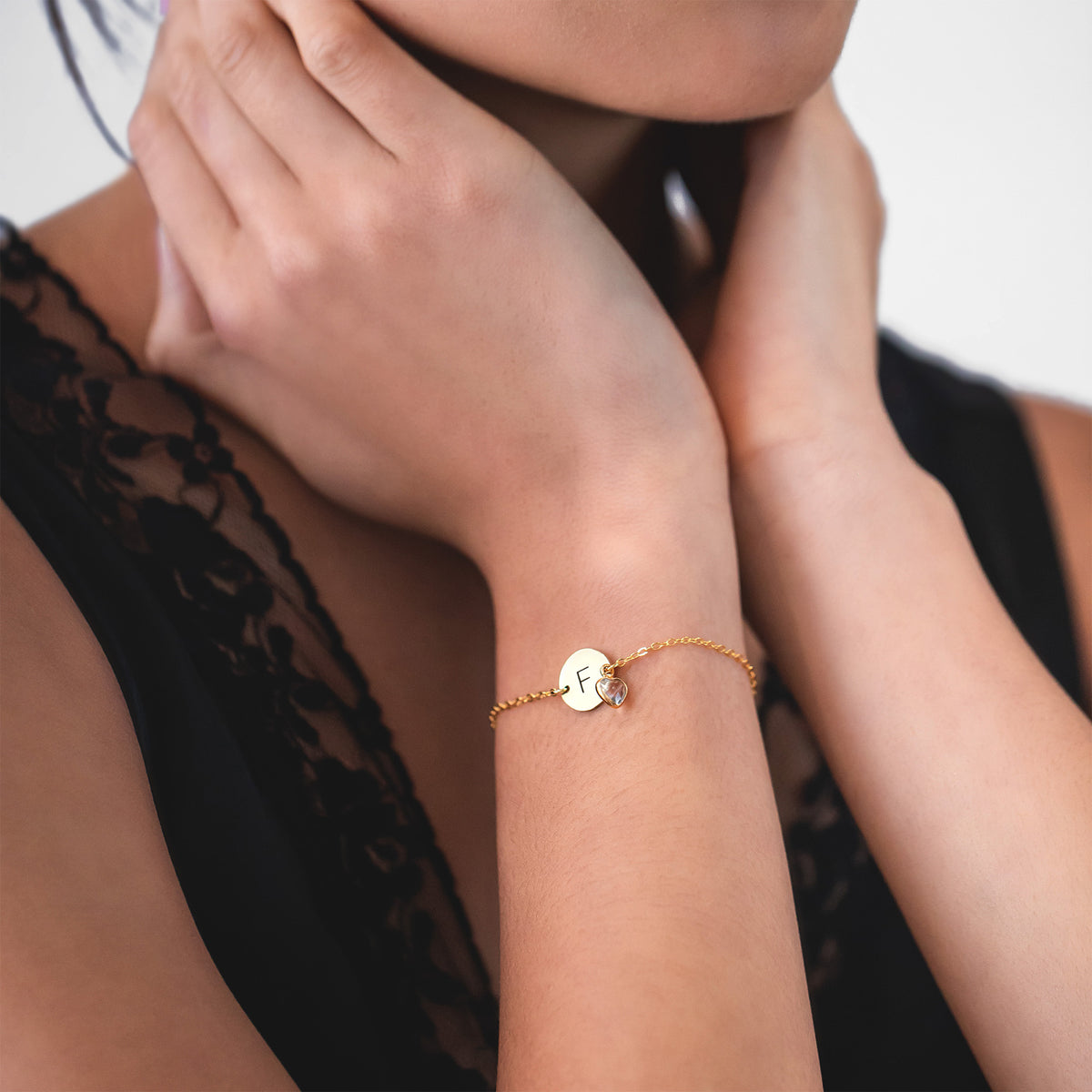 Bracelet with engraved F initial disc and clear faceted stone worn on a wrist