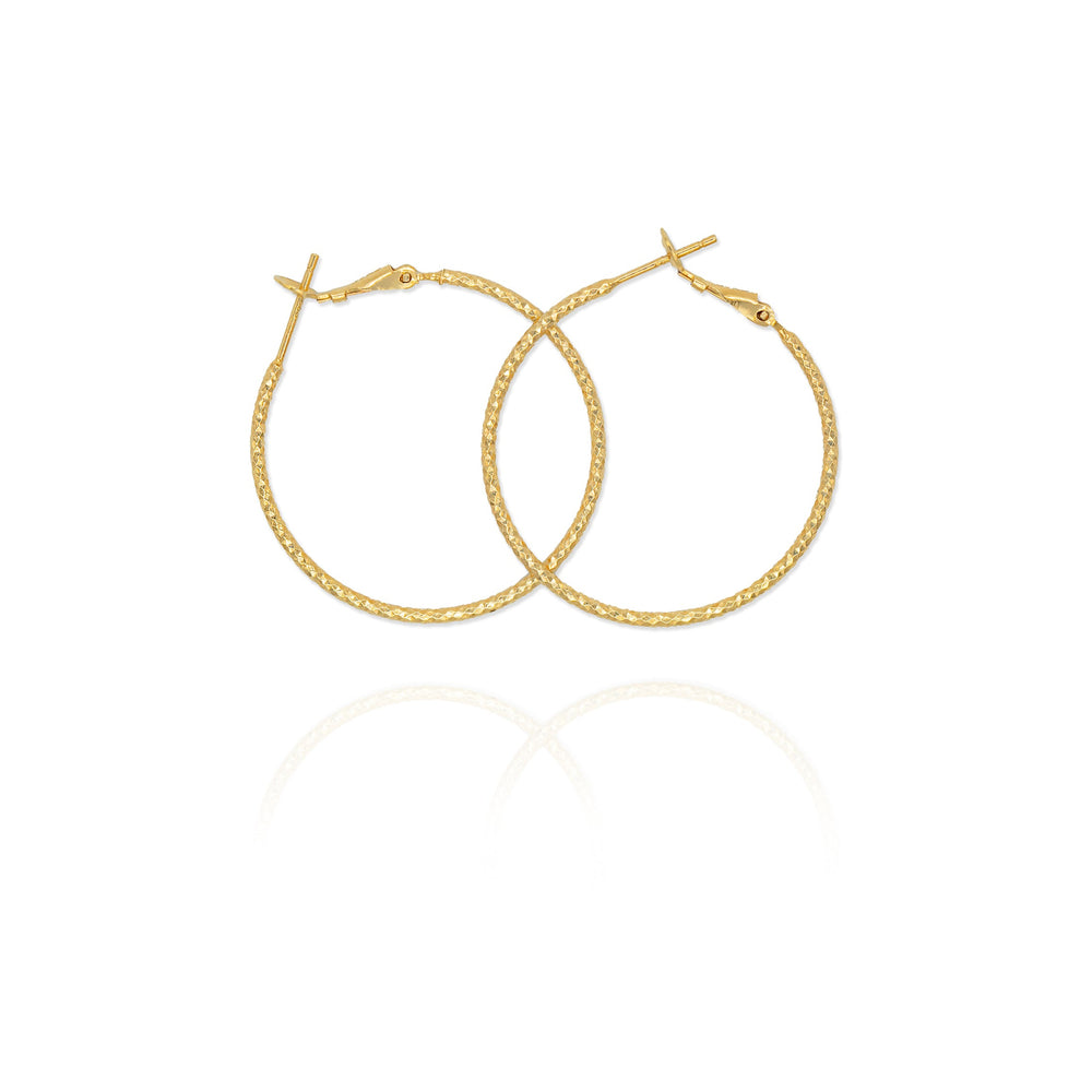 A pair of large thin hoop earrings in gold color.
