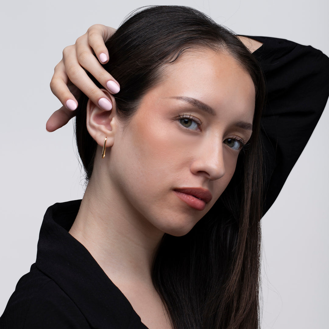 A model waring a pair of gold hoop earrings against white background