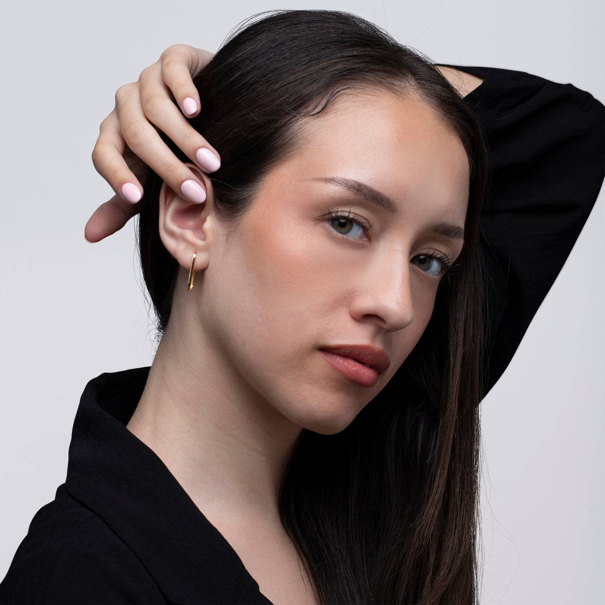 A model waring a pair of gold hoop earrings against white background