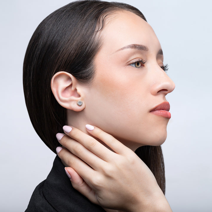Close-up of a woman wearing a diamond earring on a light gray background