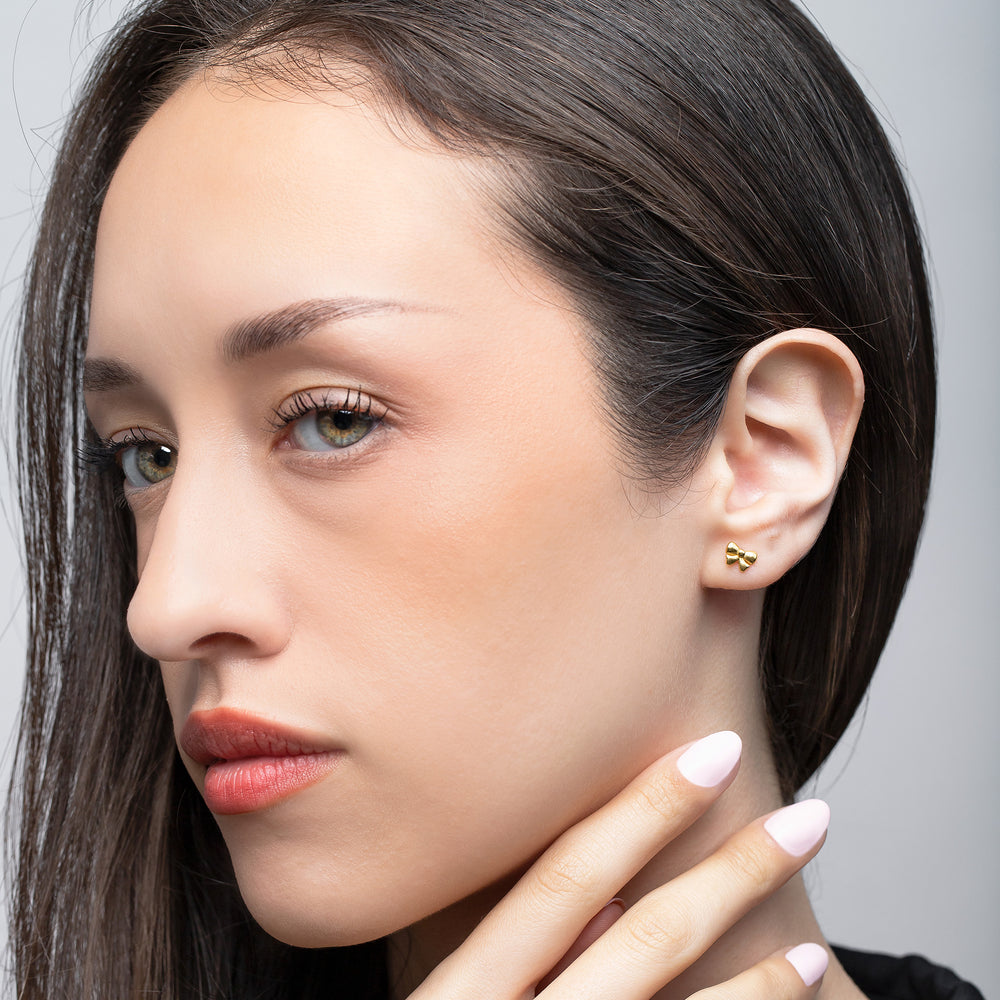 Close-up of a woman wearing gold earrings with a neutral background