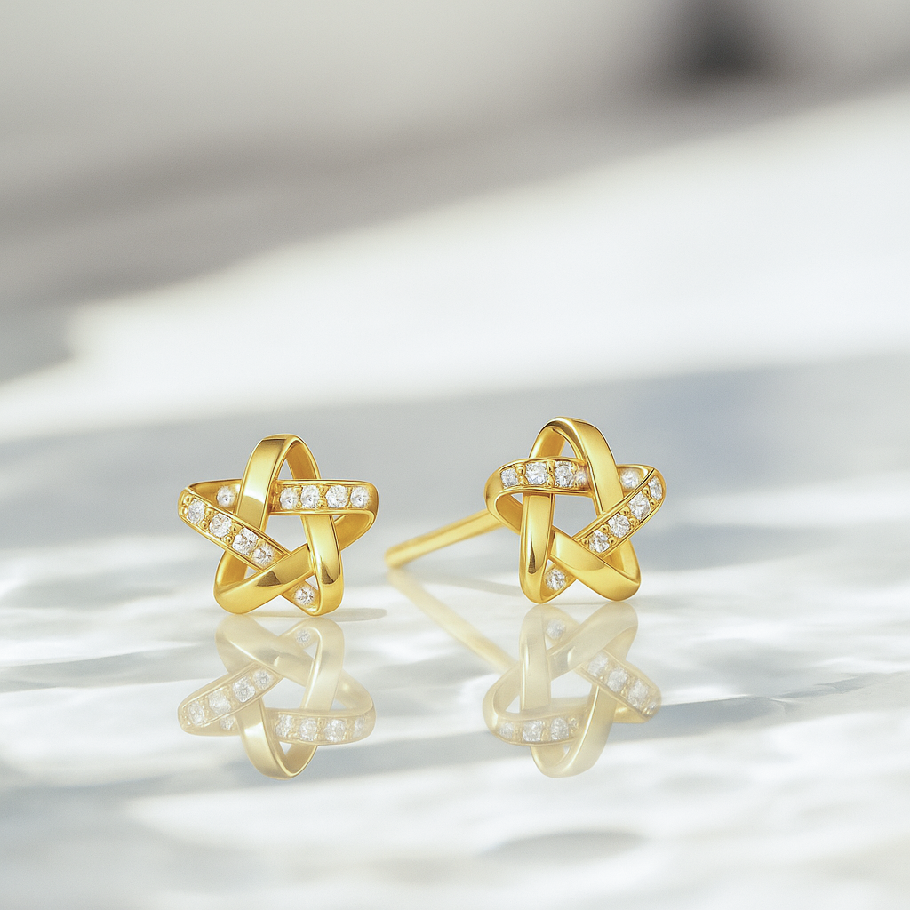 Gold earrings with star design on a reflective surface