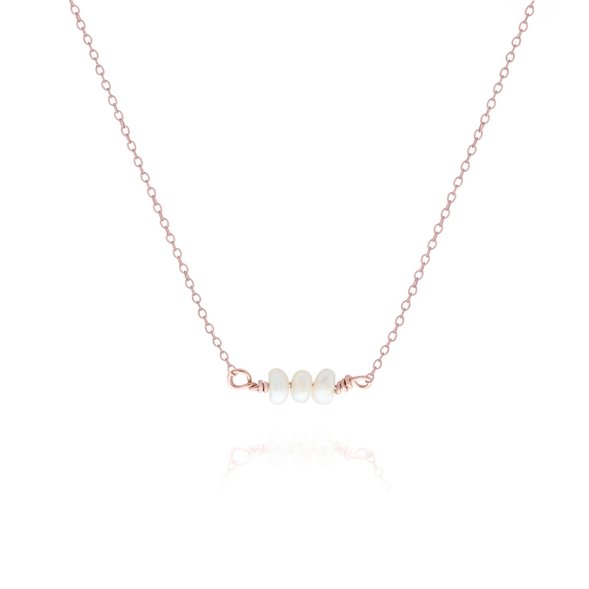 Rose-gold-tone necklace with a short row of white oval pearls on a white background