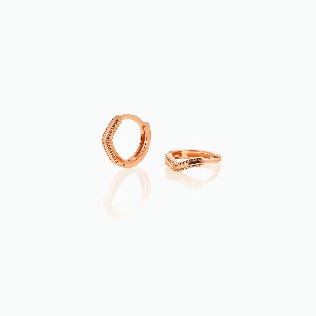 Rose gold-tone huggie hoop earrings with angled textured fronts displayed on a white background