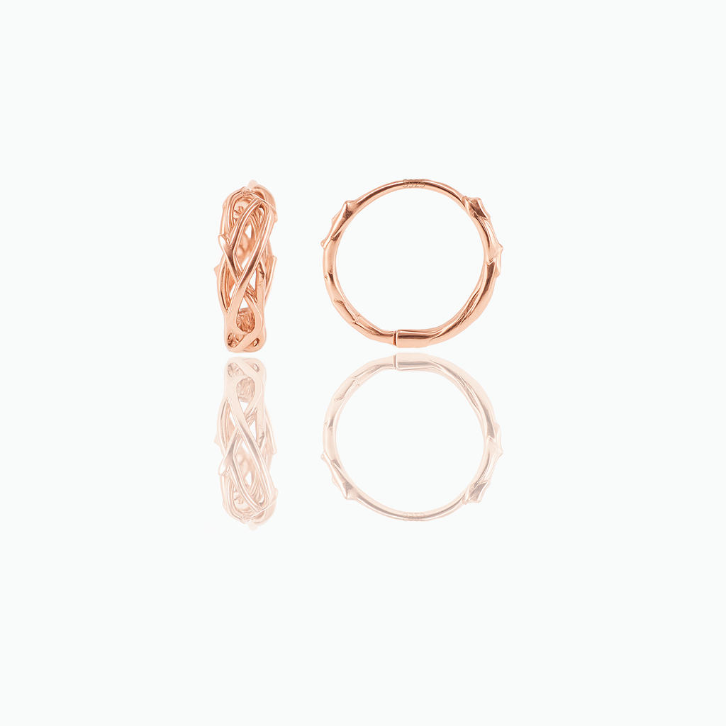 A pair of minimalist huggie hoop earrings made of rose gold, displayed against a white background.