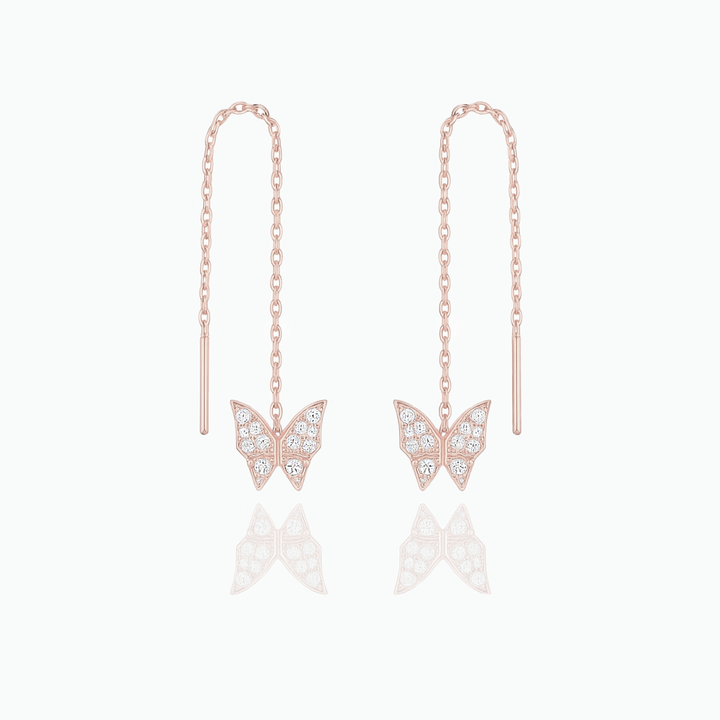 Rose gold butterfly earrings with chain drops on a white background