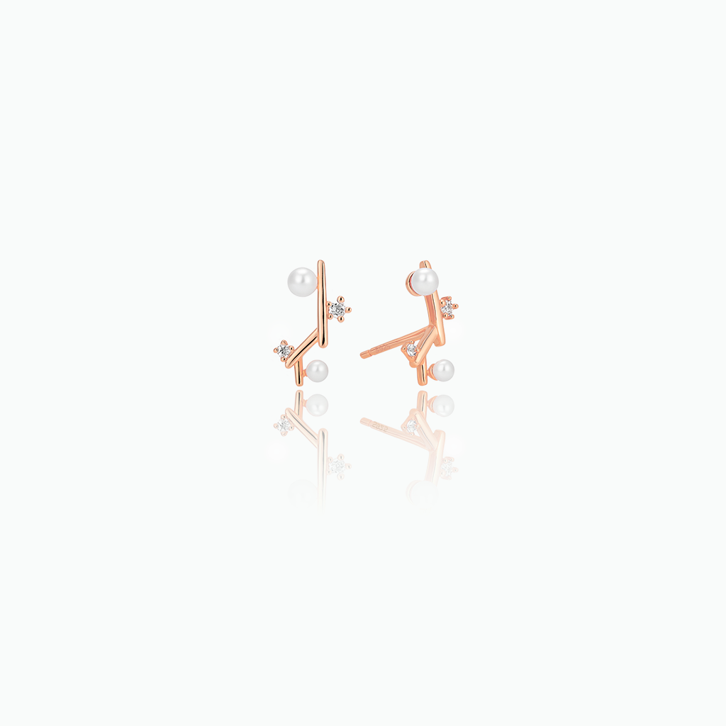 Pair of rose gold earrings with pearls on a white background
