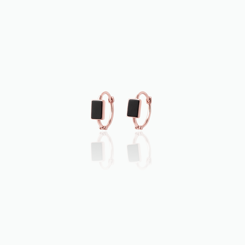 Pair of rose gold hoop earrings with black stones on a white background