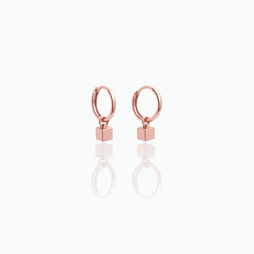 Rose gold hoop earrings with square charms on a white background
