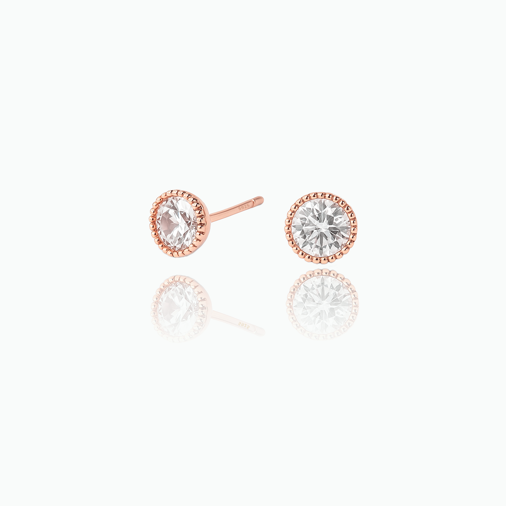 Pair of rose gold earrings with clear gemstones on a white background