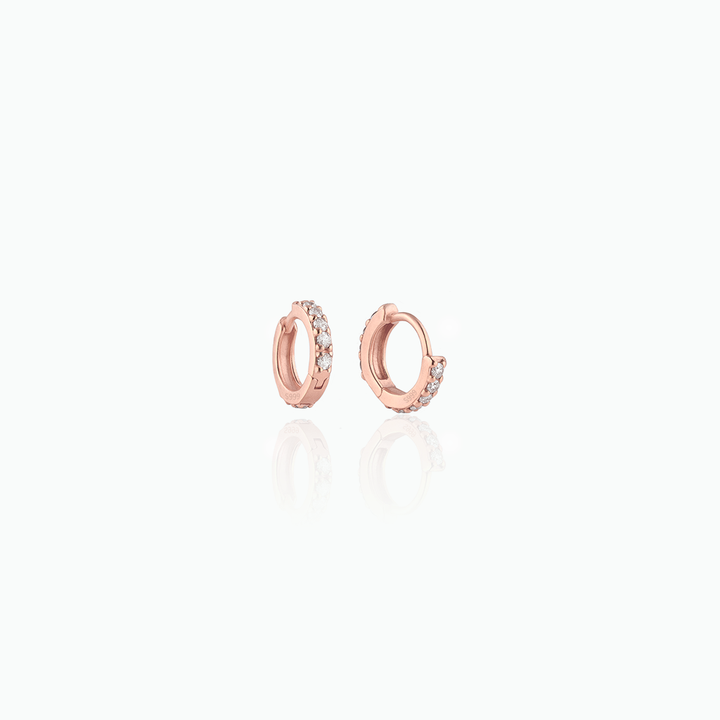 Rose gold hoop earrings with small diamonds on a white background