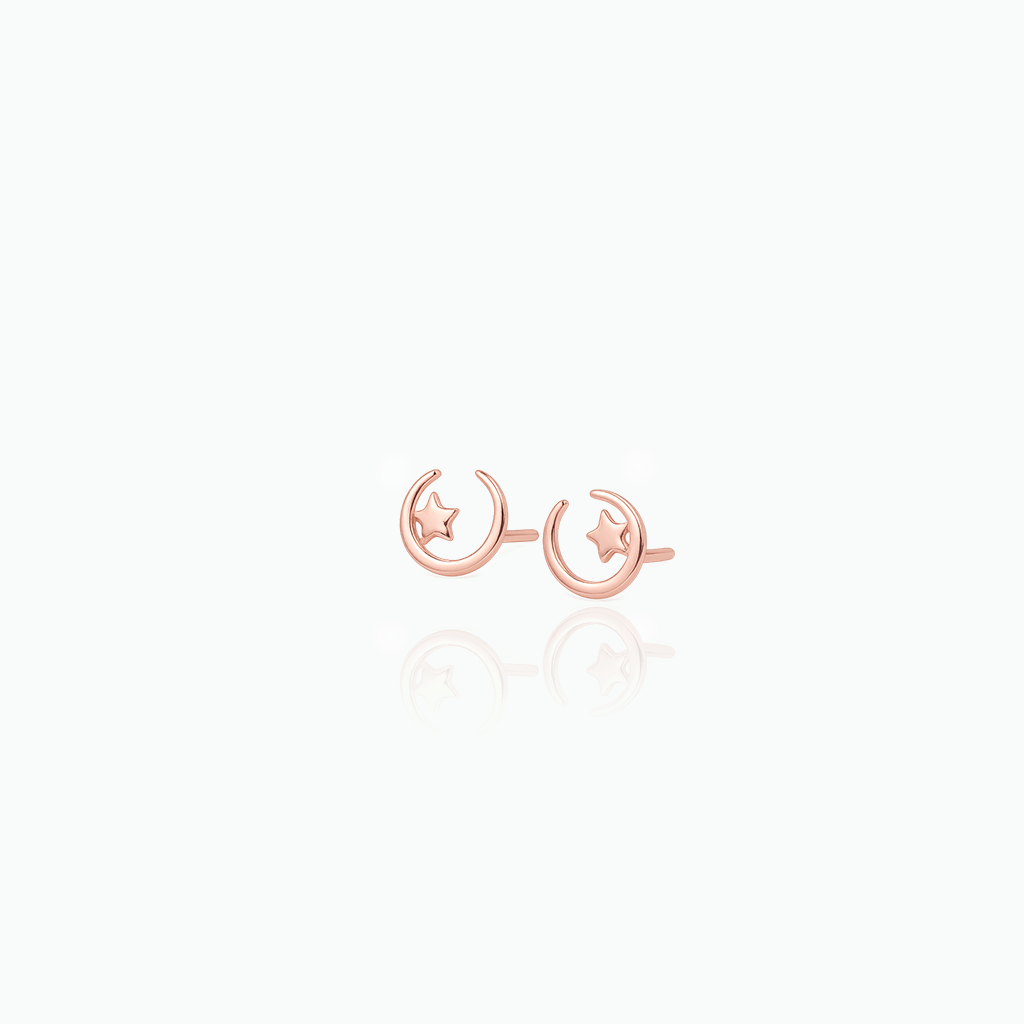 Rose gold earrings with moon and star designs on a white background