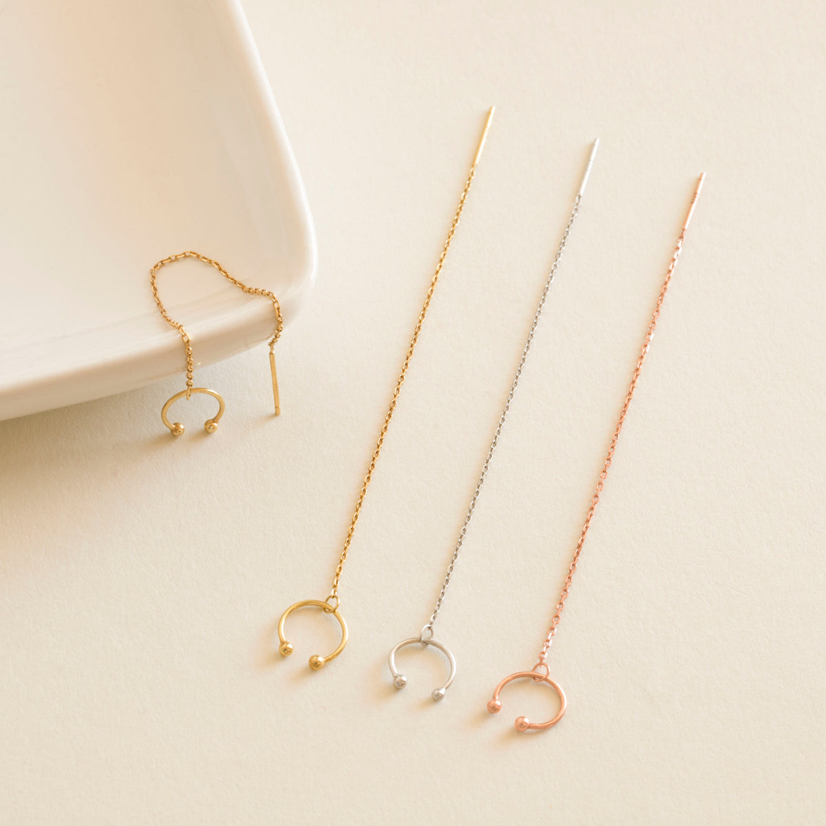 Set of gold and rose gold cuff earrings on a light beige surface