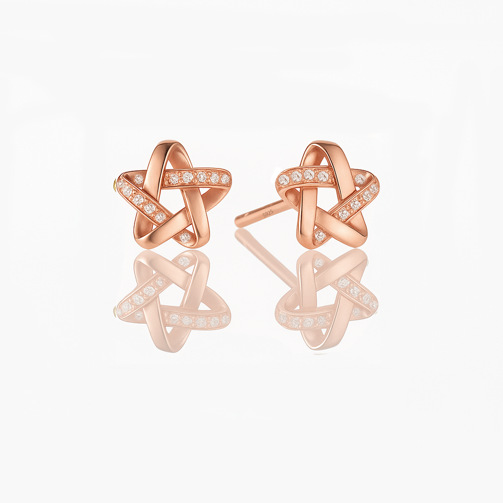 A pair of dainty sterling silver star earrings with a rose gold vermeil finish and small sparkling stones embedded in the design.