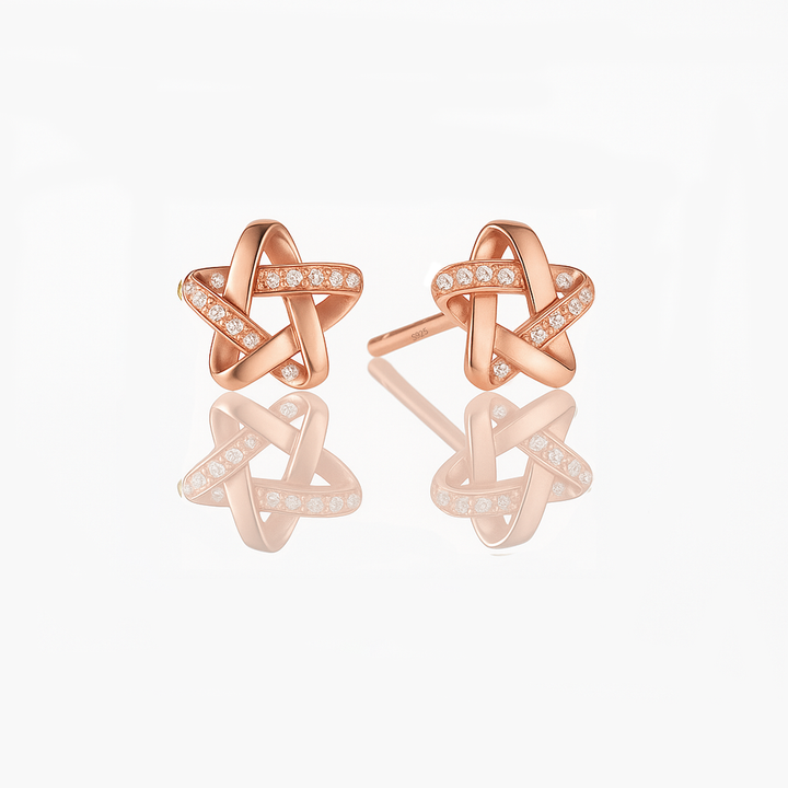 A pair of dainty sterling silver star earrings with a rose gold vermeil finish and small sparkling stones embedded in the design.