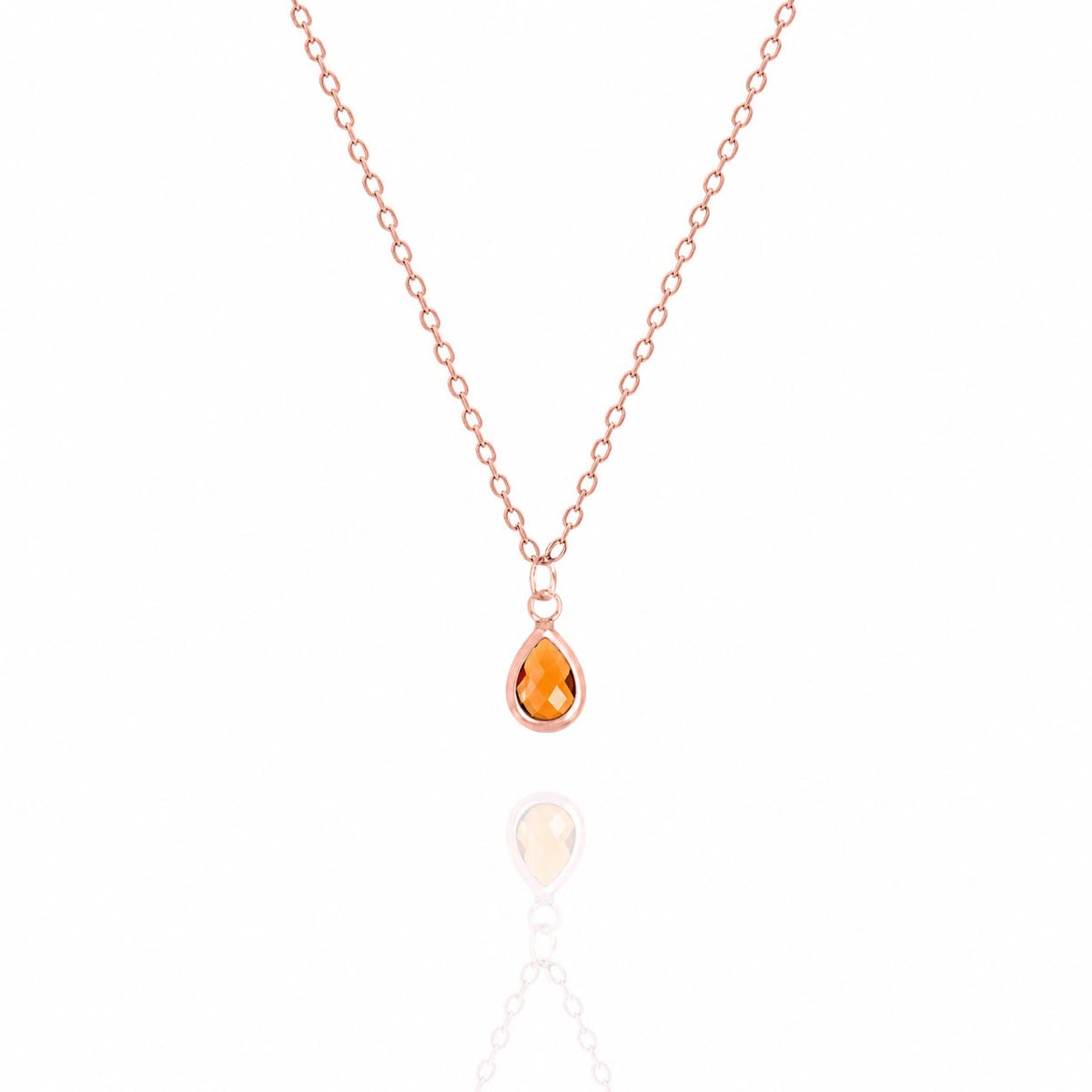 Rose-gold-tone necklace with an orange teardrop pendant on a white background