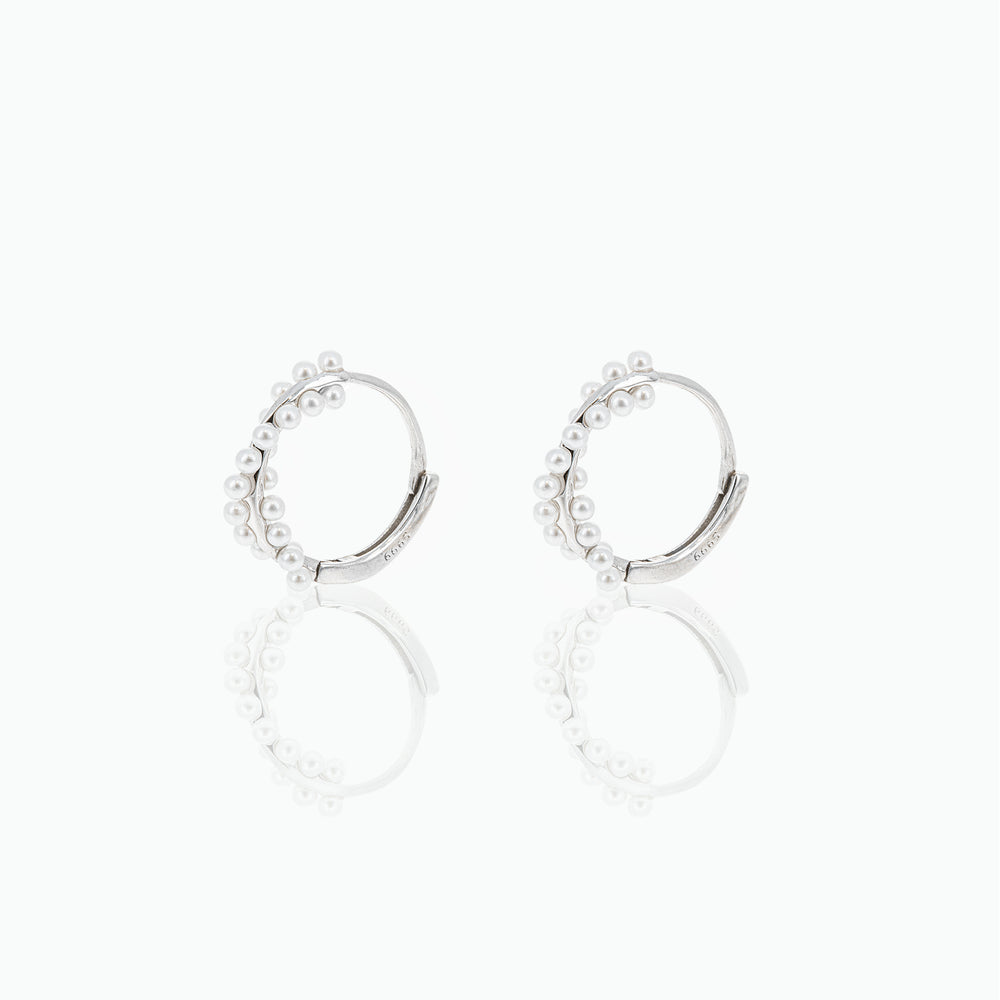 Silver hoop earrings with small pearls on a white background
