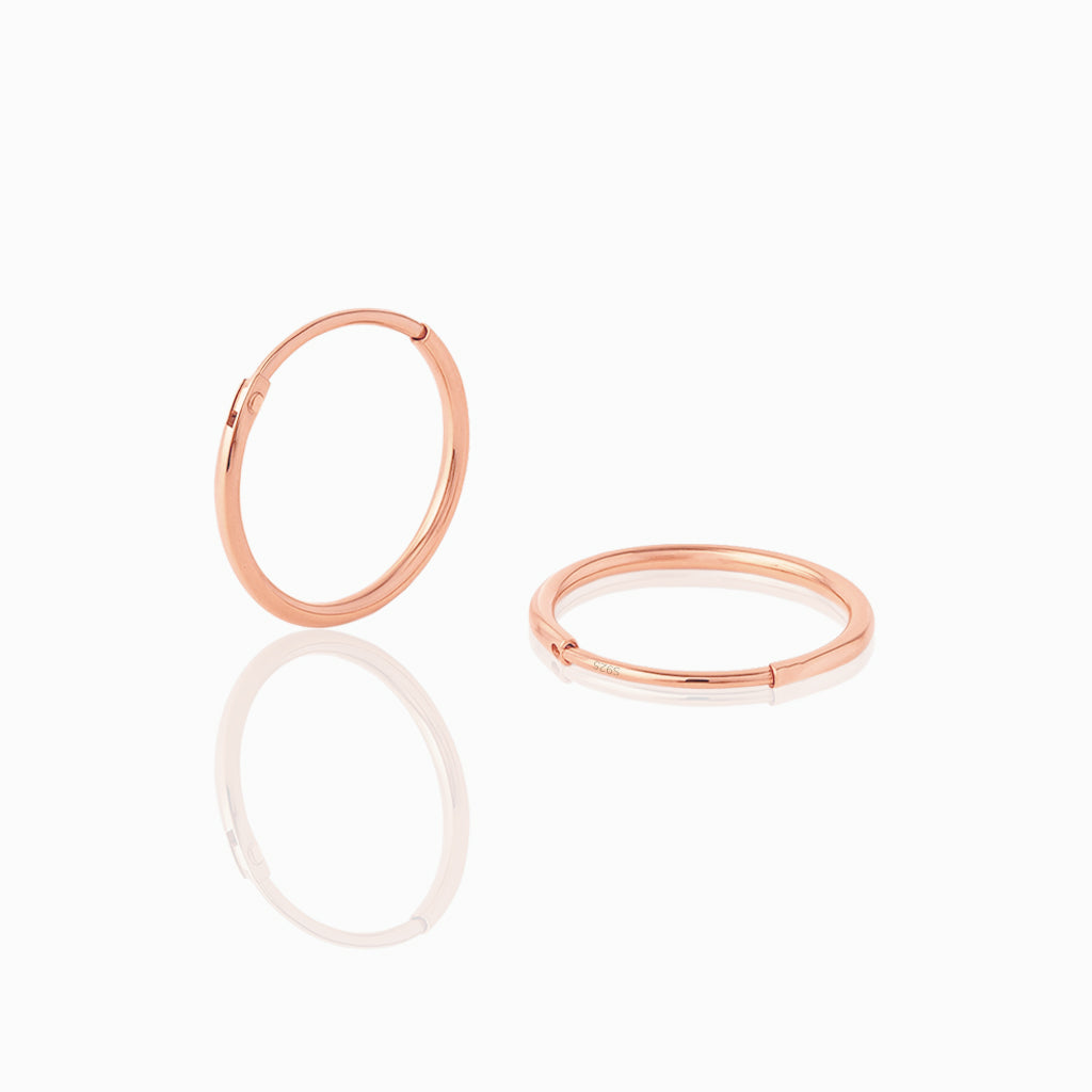 Two rose gold hoop earrings on a white background