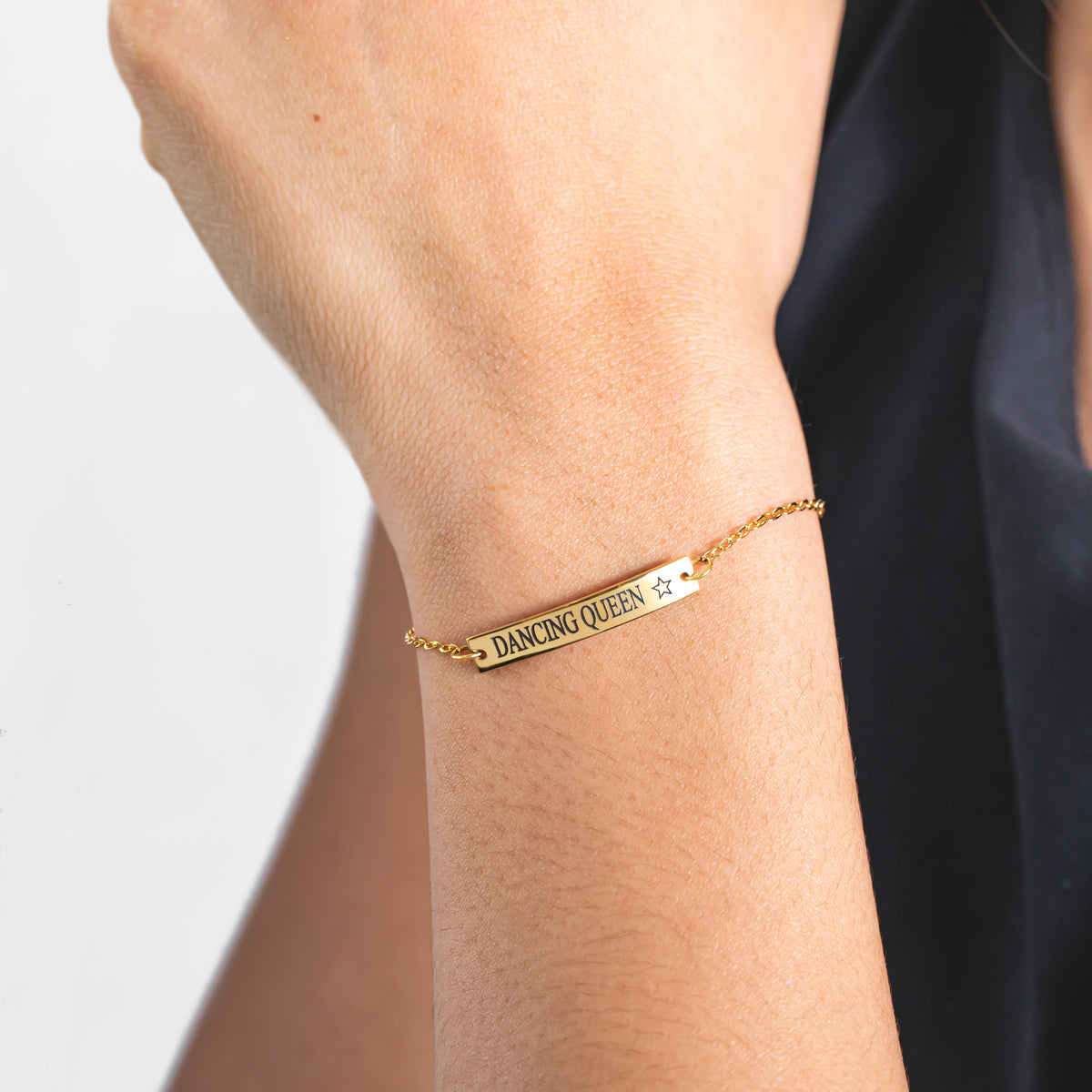 Gold-tone bar bracelet engraved DANCING QUEEN with a star worn on a wrist