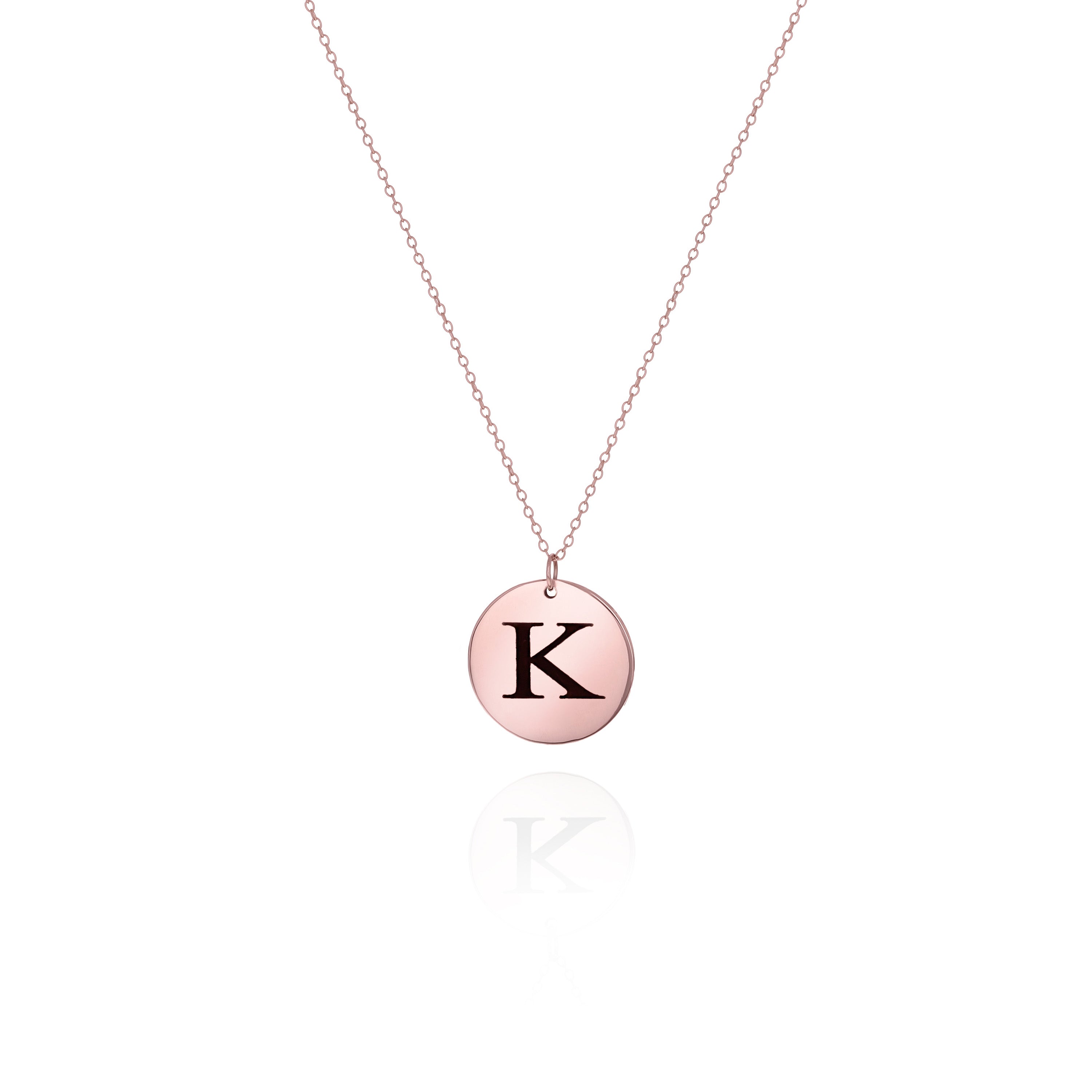 A rose gold-colored disc necklace with the initial 'K' engraved on the charm, displayed against a white background.