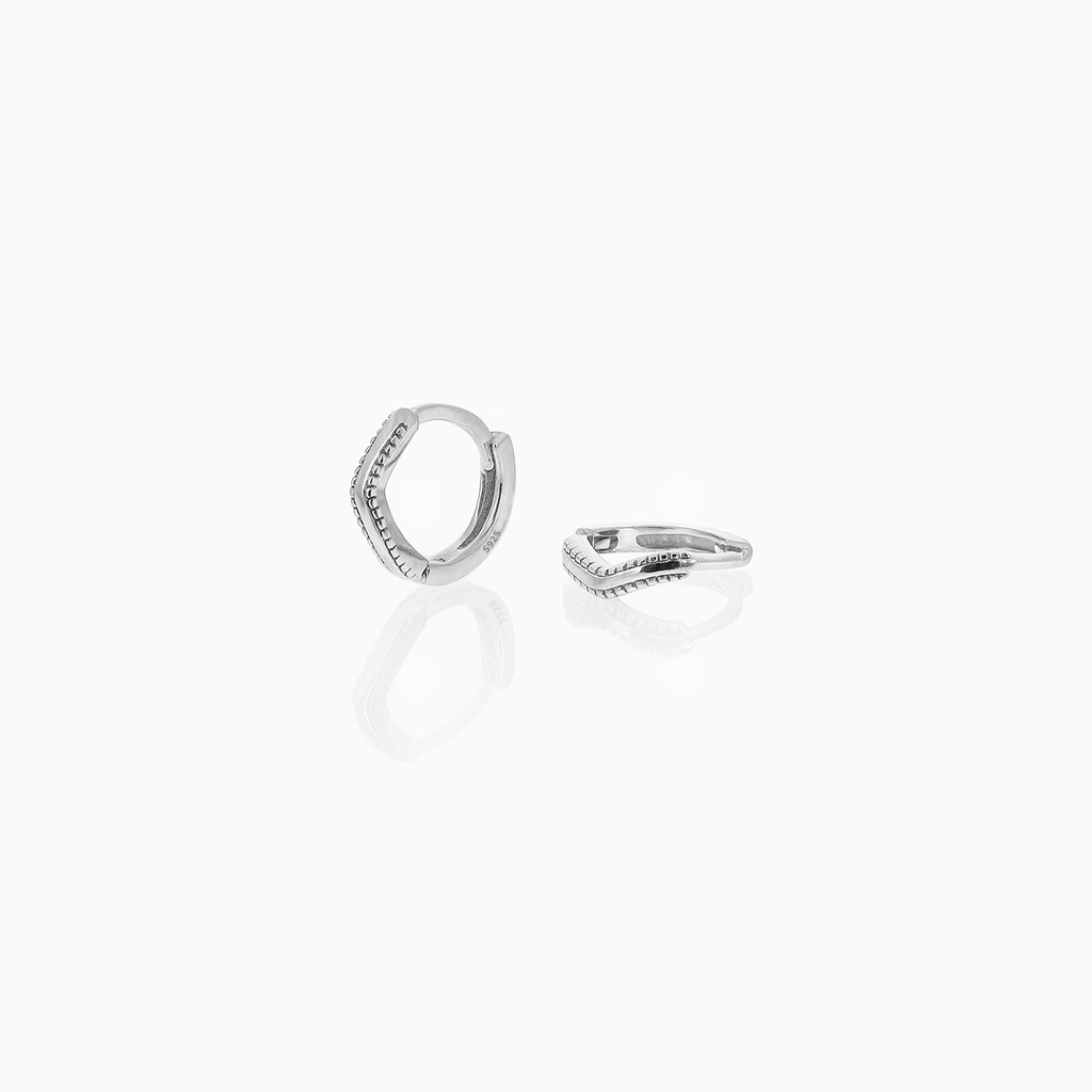 Silver-tone huggie hoop earrings with angled textured fronts displayed on a white background