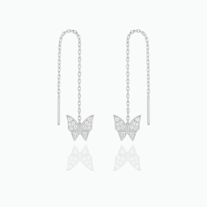 Butterfly earrings on thin chains against a white background