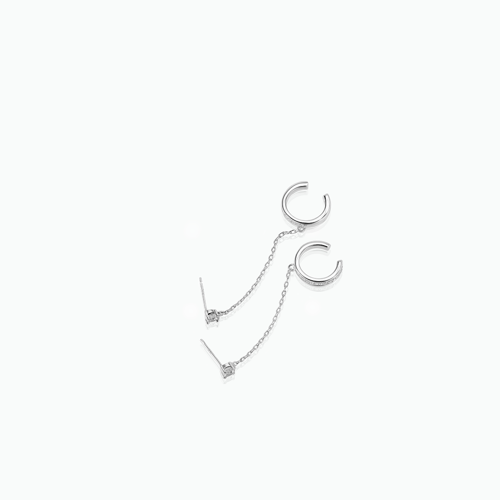 Silver cuff earrings with a chain on a white background