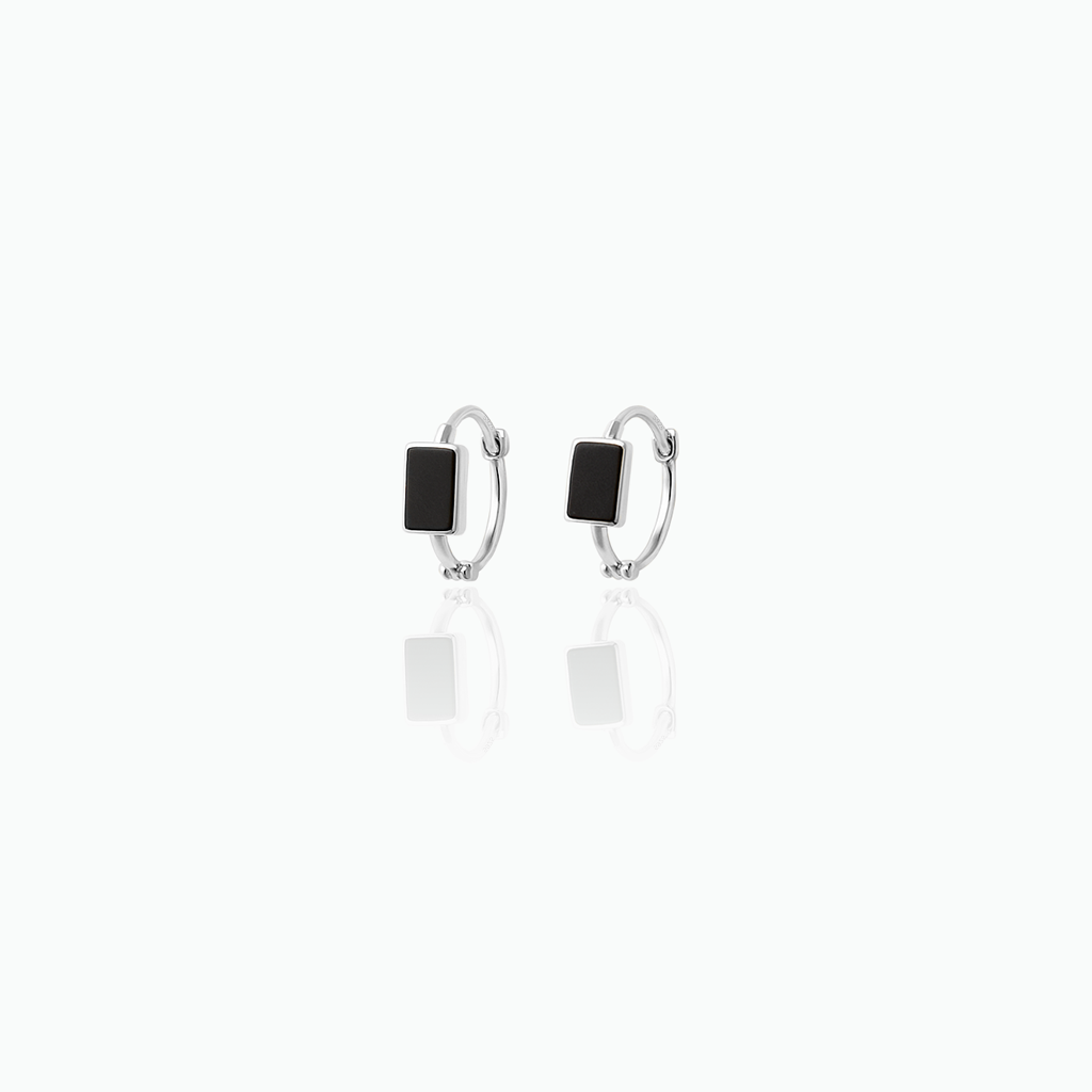 Pair of silver hoop earrings with black stones on a white background