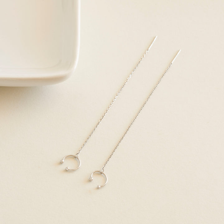 Silver chain earrings cuff on a beige surface