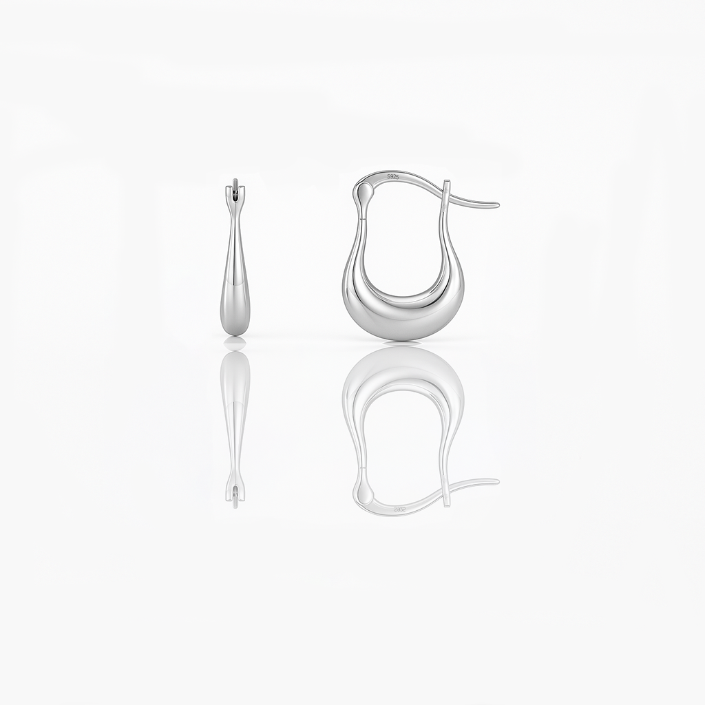 A pair of gold vermeil huggie earrings on a white background, reflecting light on their surface.