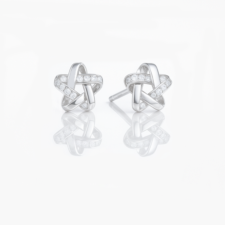 A pair of dainty sterling silver star earrings with a silver finish and small sparkling stones embedded in the design.
