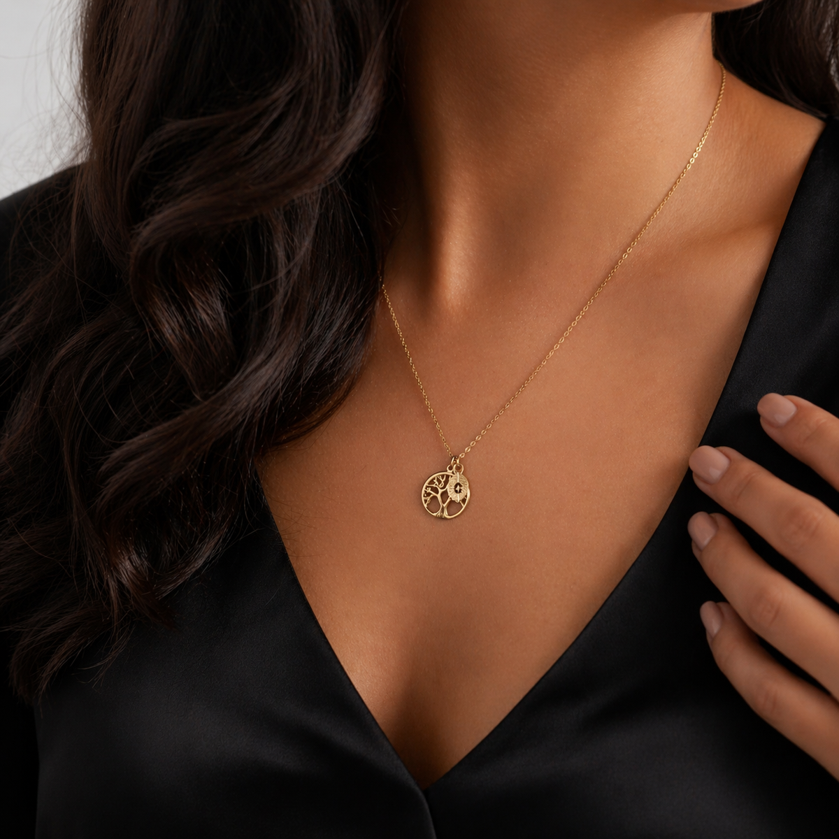 Gold-tone tree of life pendant necklace worn on the neck against a black top