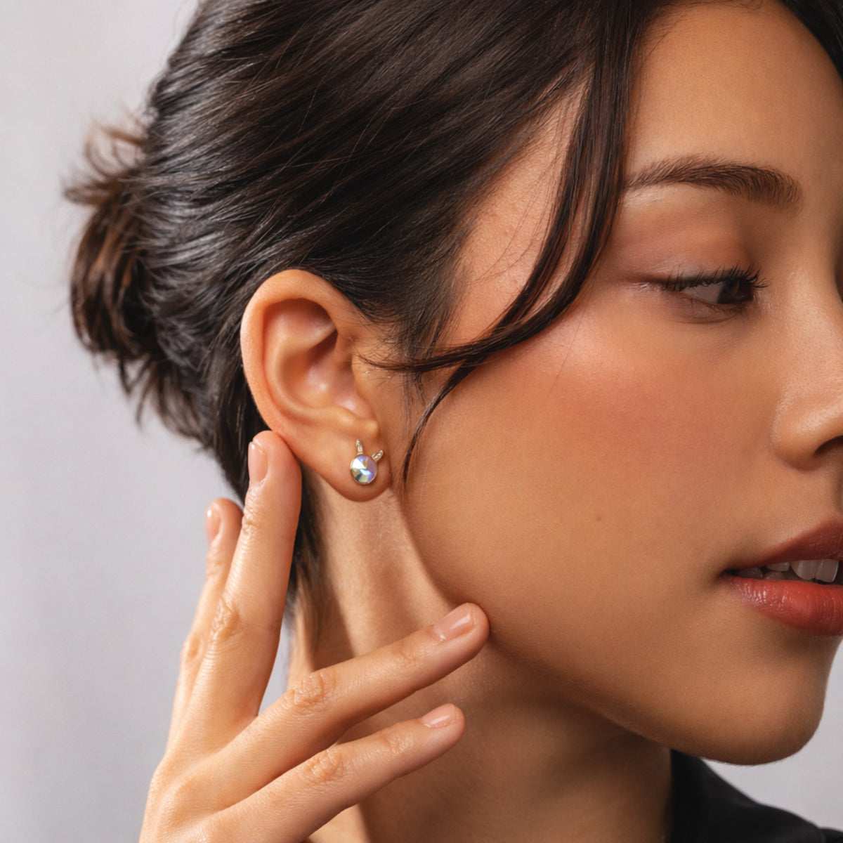 Close-up of a woman wearing an earring with a neutral background
