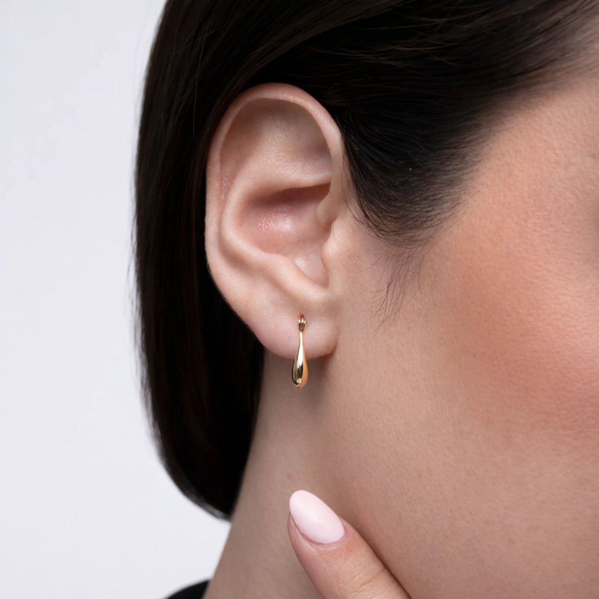 Gold earring worn by a person with a neutral background