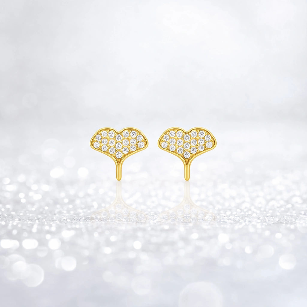 Gold-tone crystal-set whale tail stud earrings displayed upright on a sparkling white background