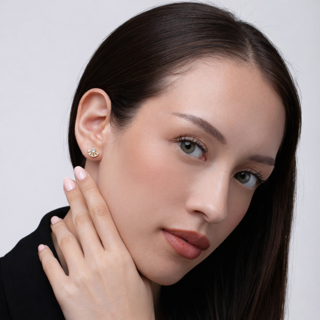Close-up of a woman wearing a gold earring against a neutral background