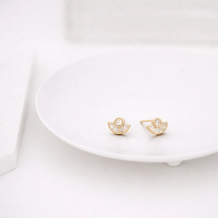 Gold earrings on a white dish with a white background