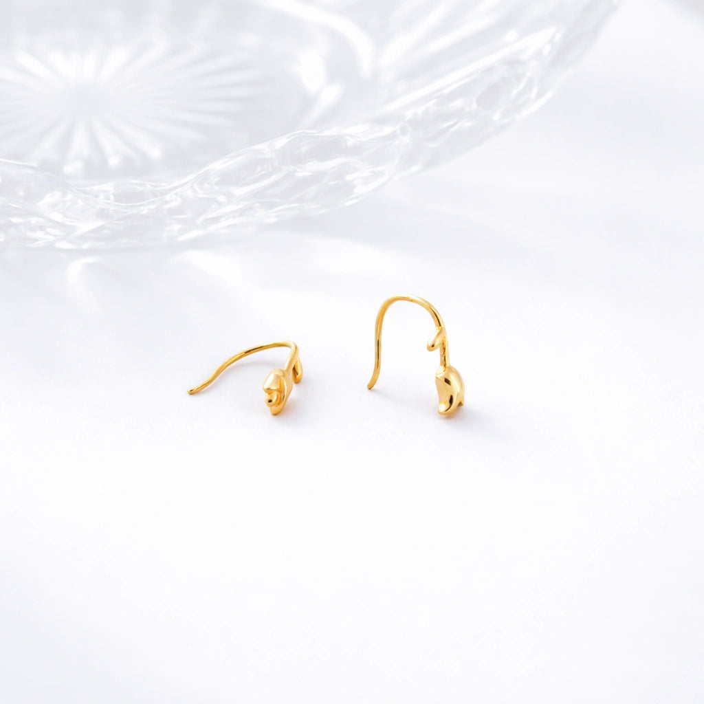 Gold-tone tulip dangle hook earrings displayed on a white textured surface