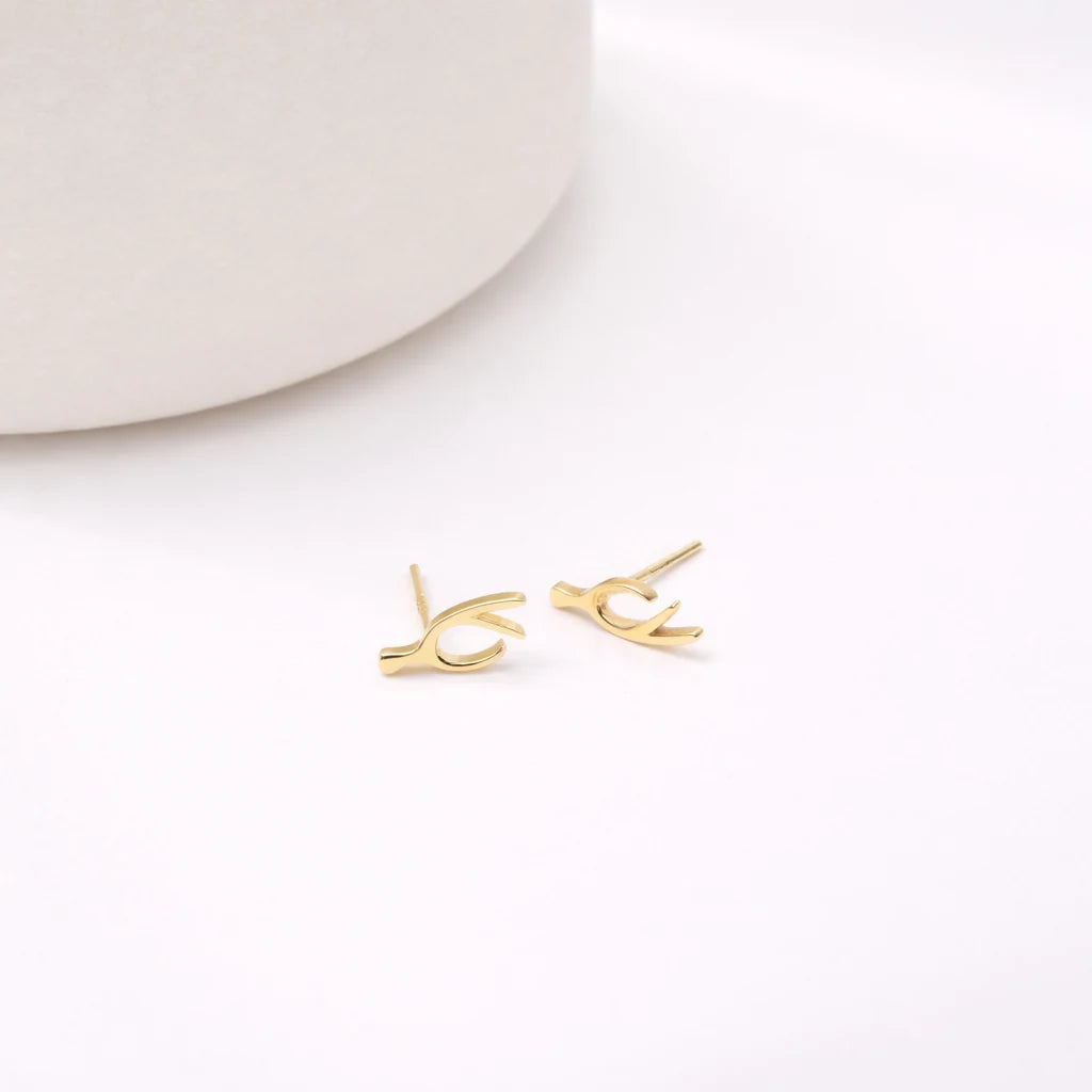 Gold-tone branch-shaped stud earrings displayed on a pale surface