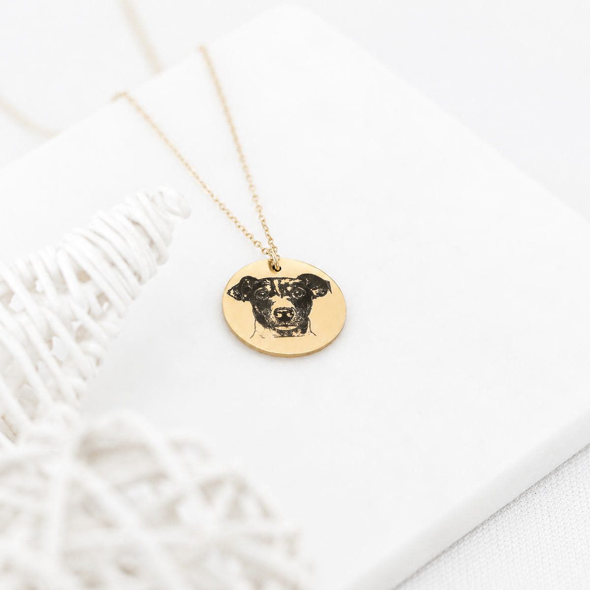 Gold-tone round pendant necklace featuring a dog portrait displayed on a white surface
