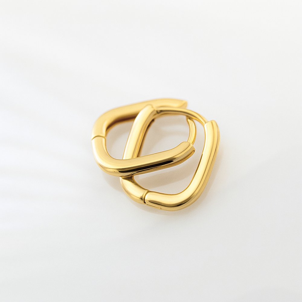 Gold hoop earring on a light gray background